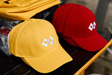 Yellow and red SOFTSWISS-branded caps displayed on a table.